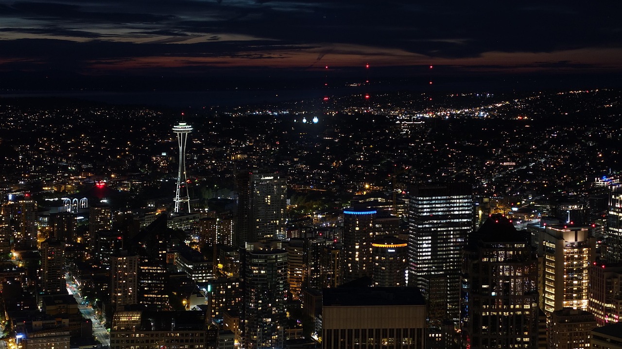 Nighttime cityscape of Seattle with the Space Needle prominently visible.