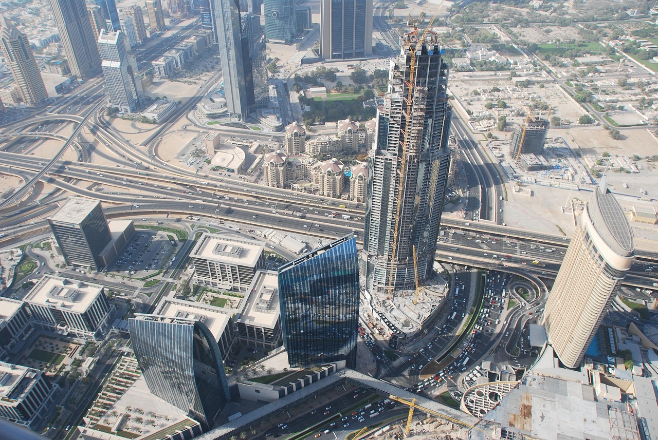 Aerial view of a bustling city with highways, skyscrapers, and construction sites.