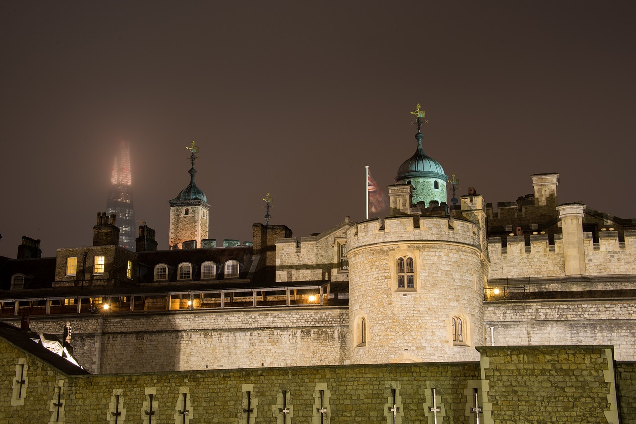 Night view of the Tower of London with a modern skyscraper in the background.