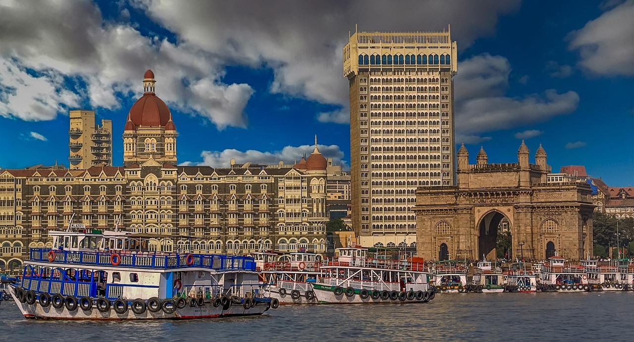 A waterfront view of Mumbai with the Gateway of India and the Taj Mahal Palace Hotel in the background.