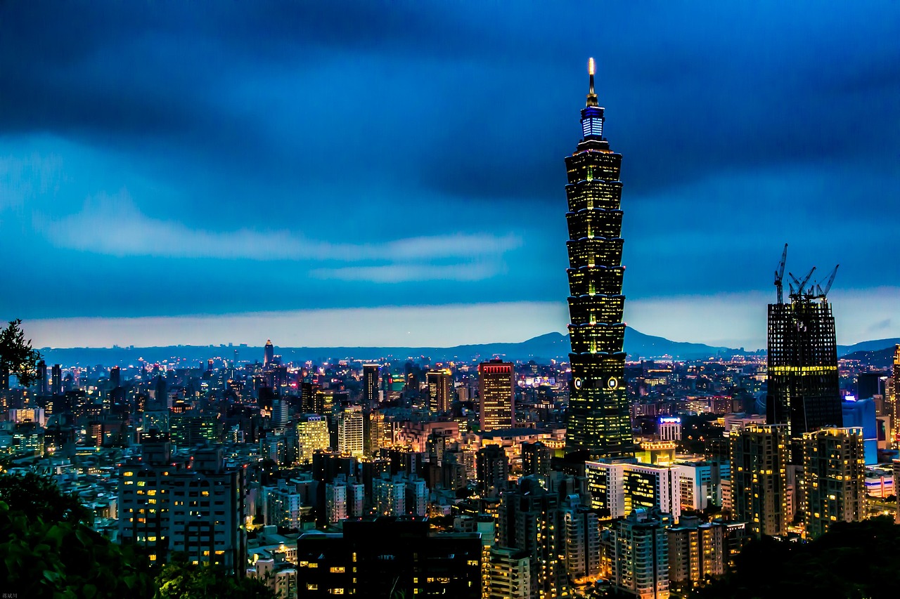 A nighttime cityscape featuring a tall skyscraper prominently lit up against a dark sky.
