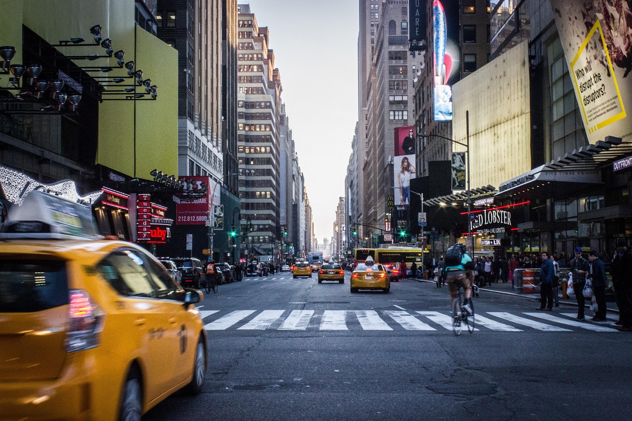 A bustling city street with yellow taxis, tall buildings, and numerous advertisements.