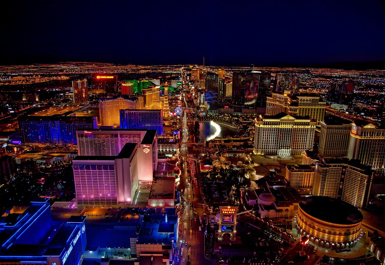 A nighttime aerial view of a bustling city with brightly lit buildings and busy streets.