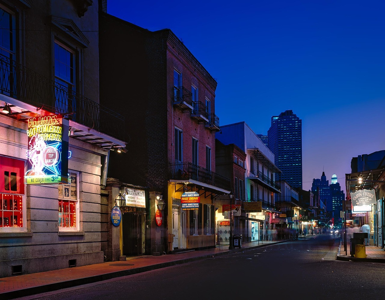 A nighttime street scene in a city with neon signs and buildings, likely in a lively district.