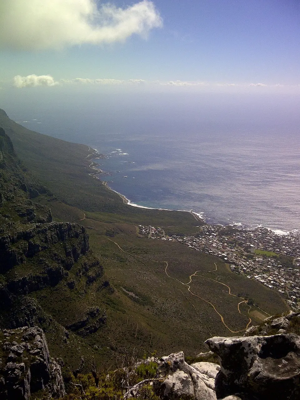 A panoramic view of a coastal town nestled between mountains and the ocean.