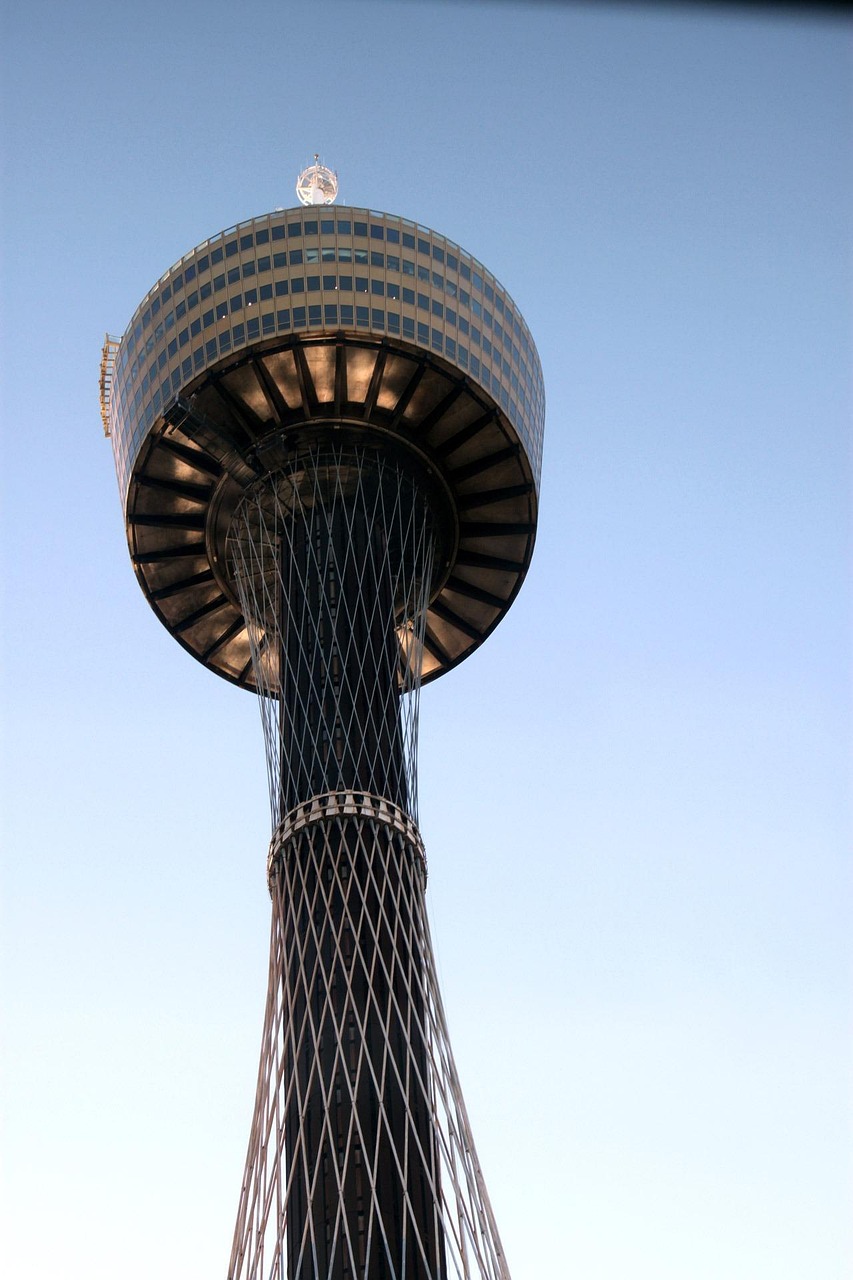 A tall tower with a circular observation deck and a spire on top, set against a clear blue sky.