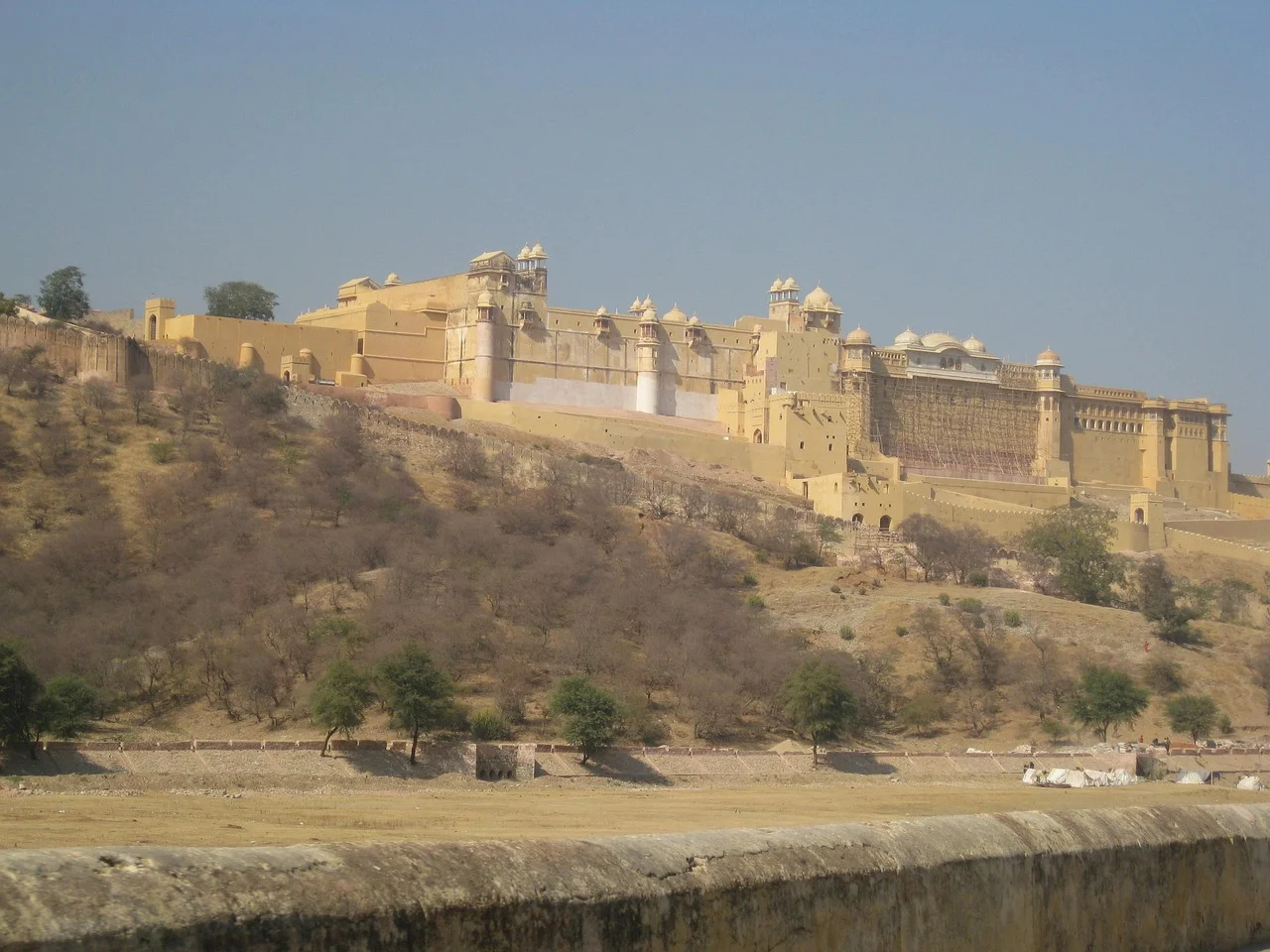 A large, historic fort on a hillside in a desert landscape.