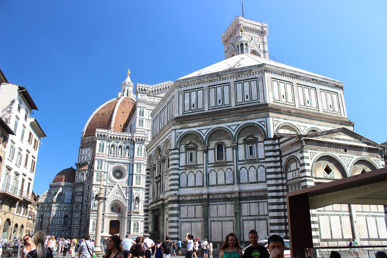 A large, ornate cathedral with a dome and intricate facade, surrounded by tourists in a bustling square.