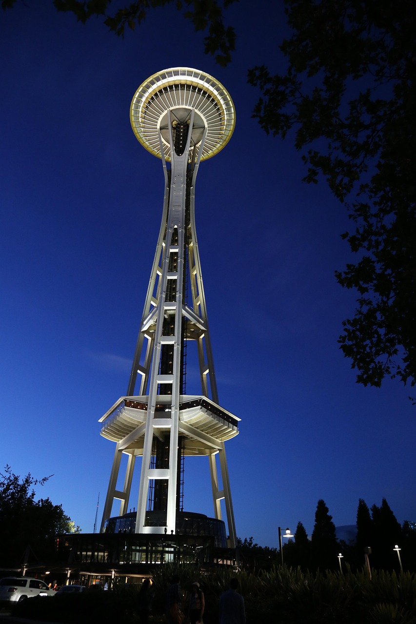 The Space Needle illuminated at night with a clear blue sky in the background.