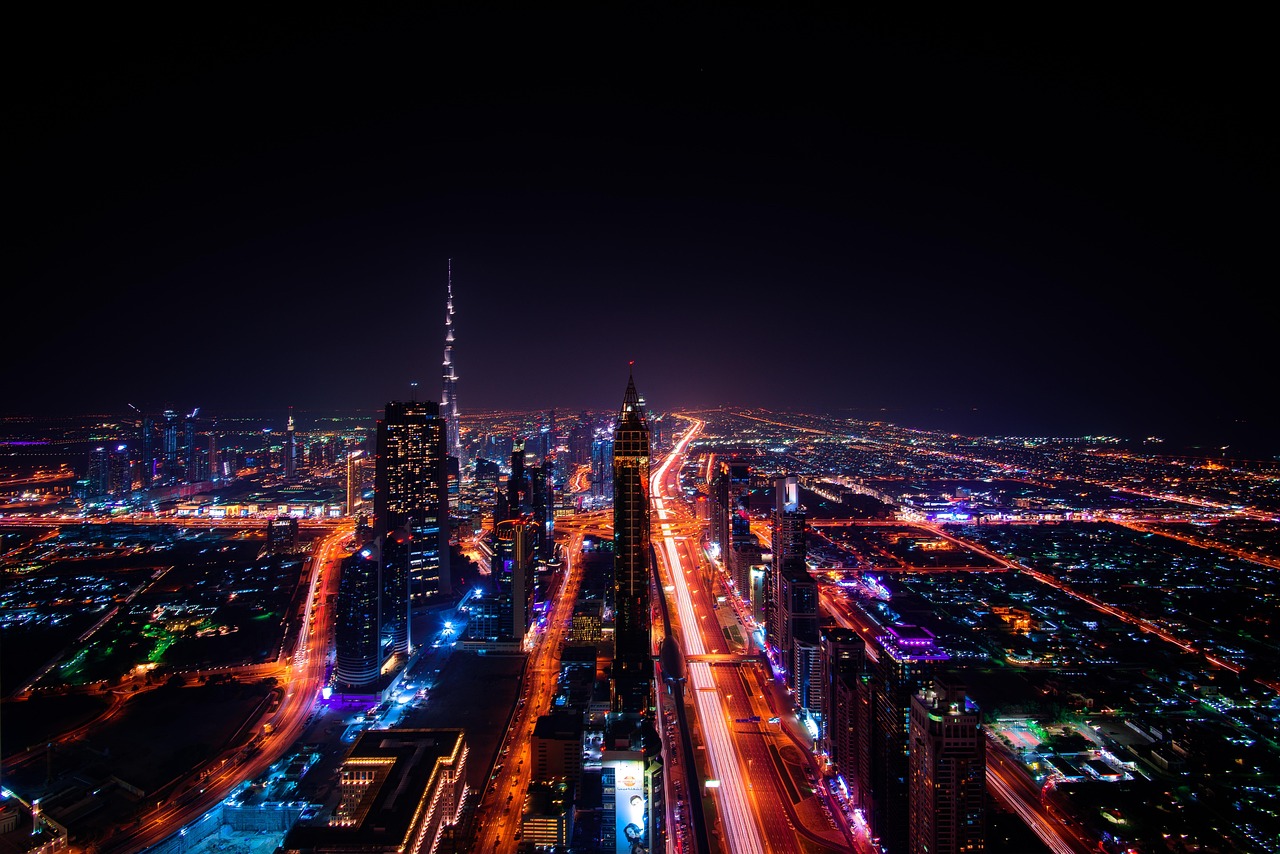 Night view of a bustling city with tall skyscrapers and illuminated highways.