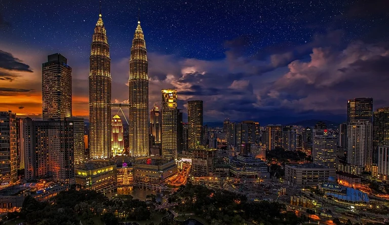 Night view of the Kuala Lumpur skyline with the Petronas Twin Towers prominently lit up.