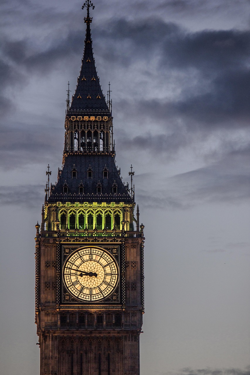 A tall clock tower with a pointed spire against a cloudy sky.
