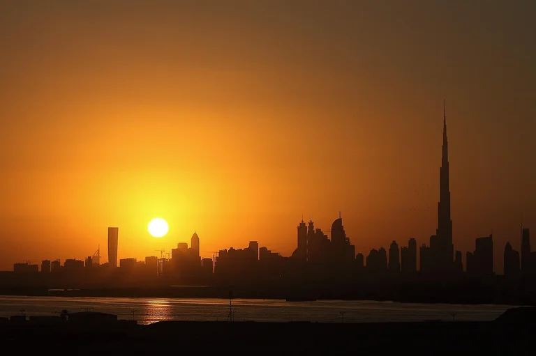 A sunset over a city skyline with tall buildings and a prominent tower on the right.