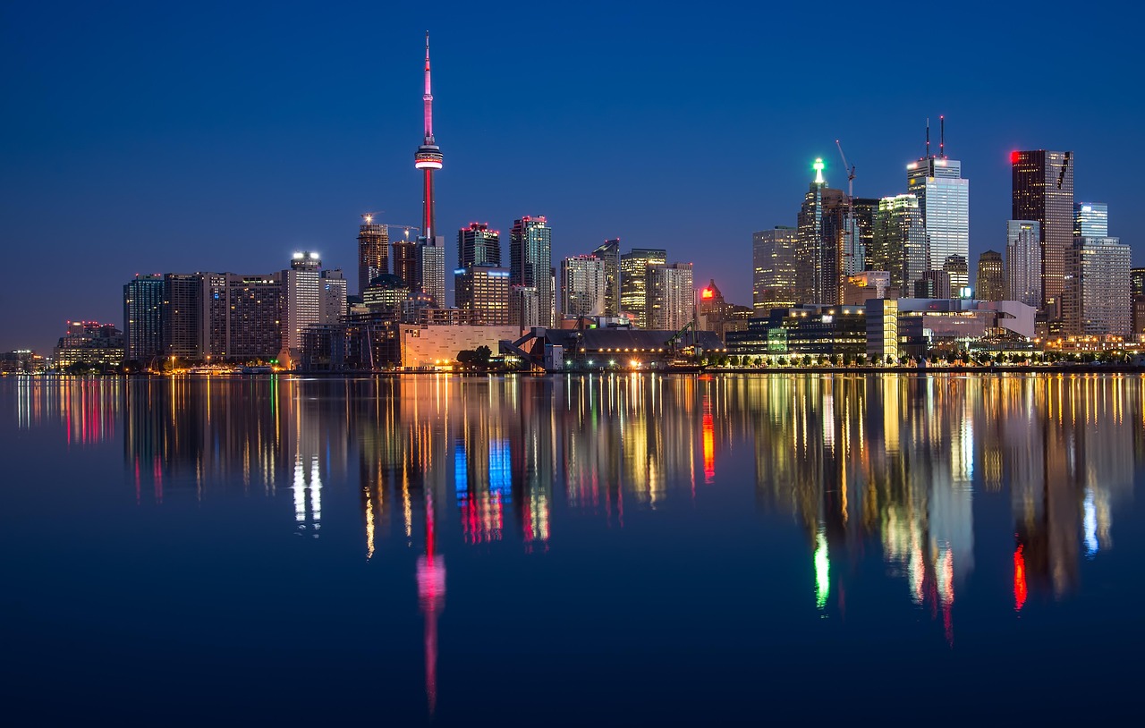 Nighttime cityscape of Toronto with the CN Tower and reflections in the water.