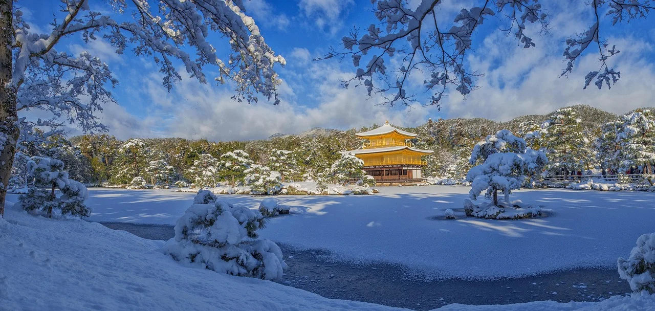 A snowy landscape with a traditional Japanese building in the background, likely Kinkaku-ji in Kyoto.