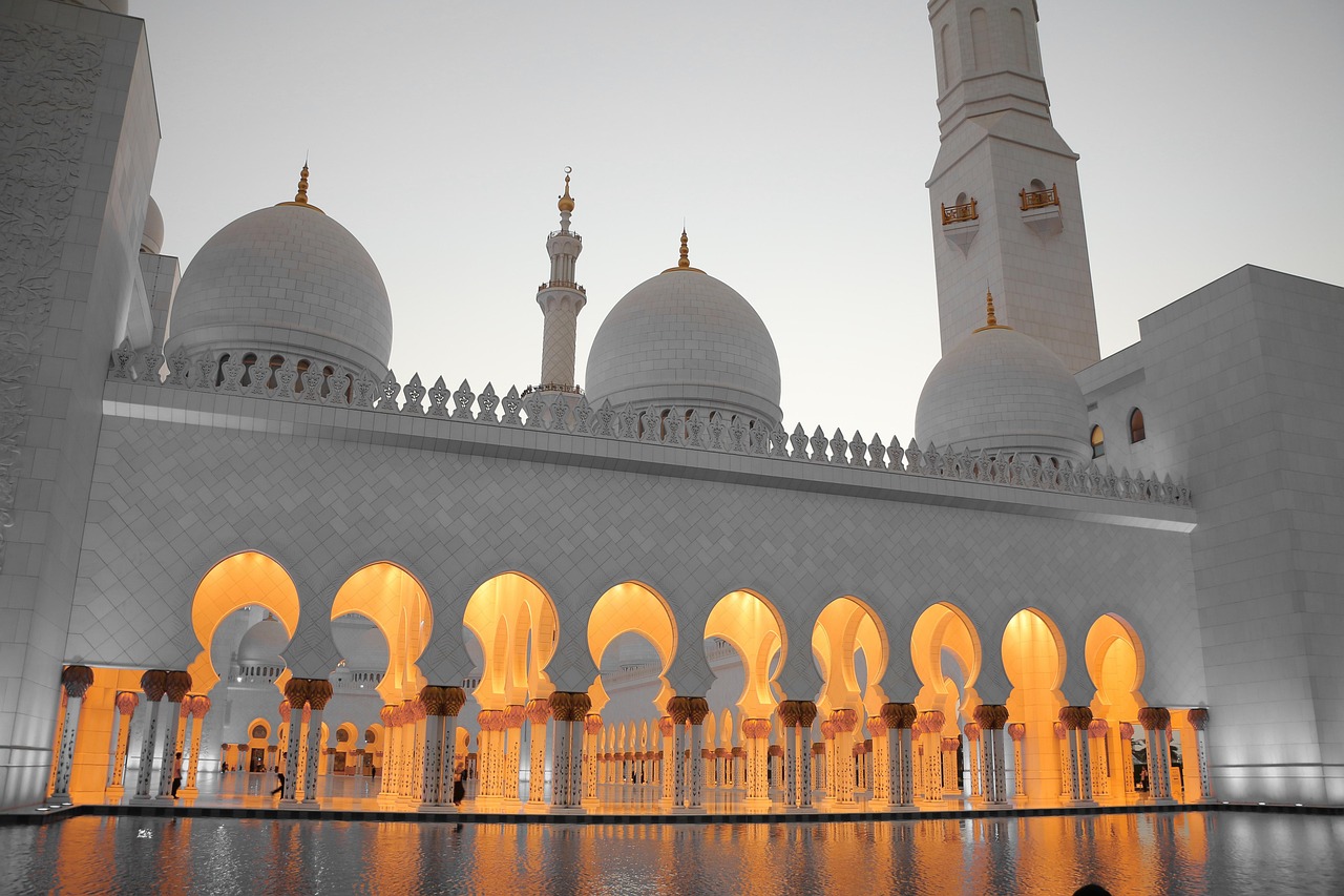 A grand mosque with illuminated arches and domes at night.