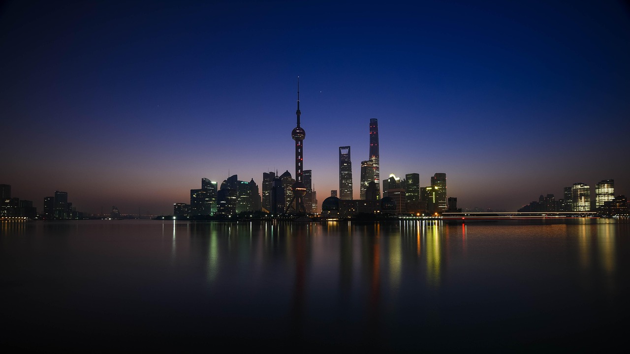 Nighttime cityscape of Shanghai with a reflection in the water.