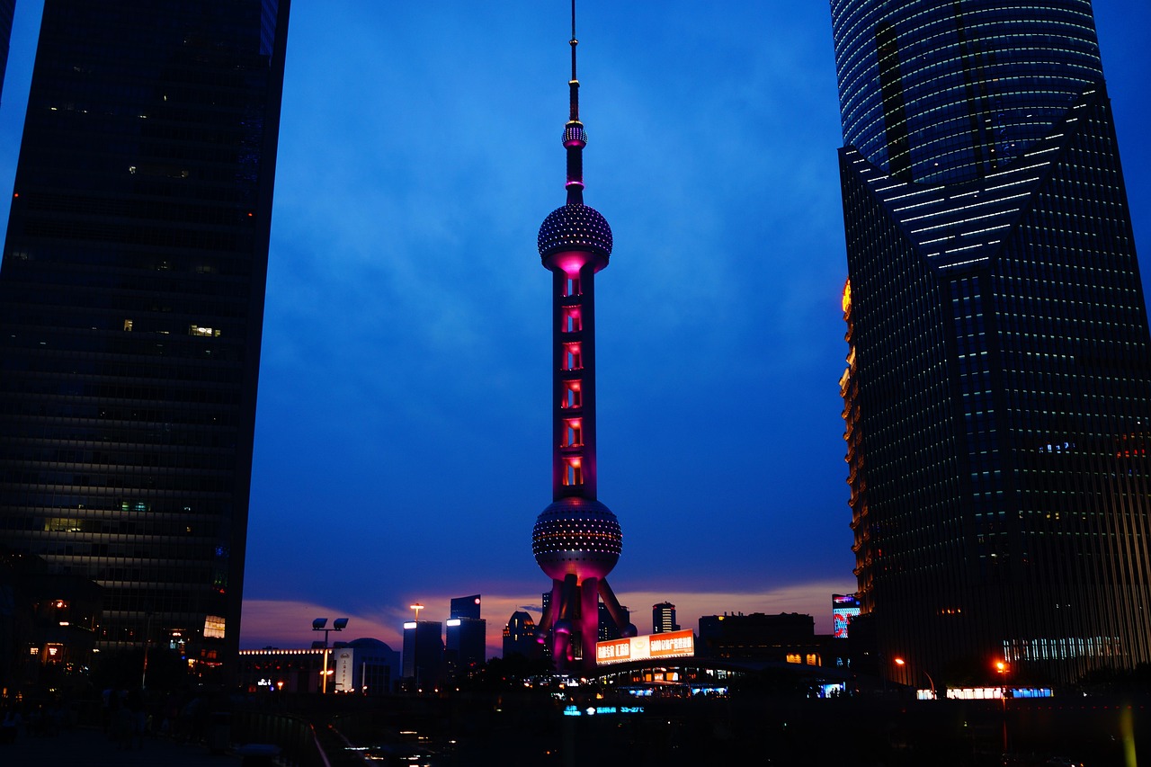 Night view of the Oriental Pearl Tower in Shanghai with surrounding skyscrapers.