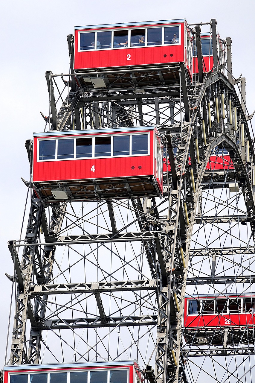 A ferris wheel with red cabins against a cloudy sky.