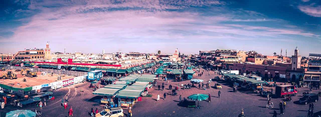 A bustling marketplace in Marrakech, Morocco with various stalls and people walking around.