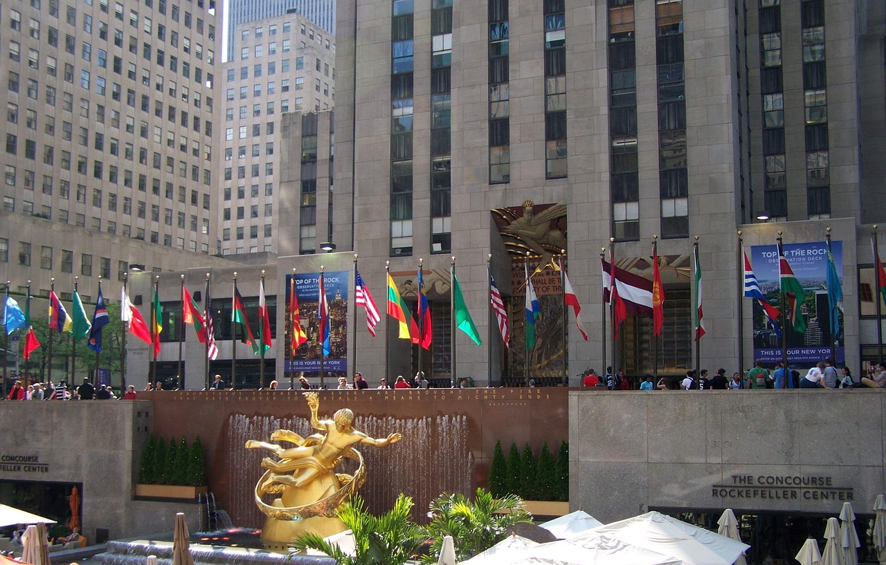 Prometheus statue at Rockefeller Center with tall buildings and flags in the background.