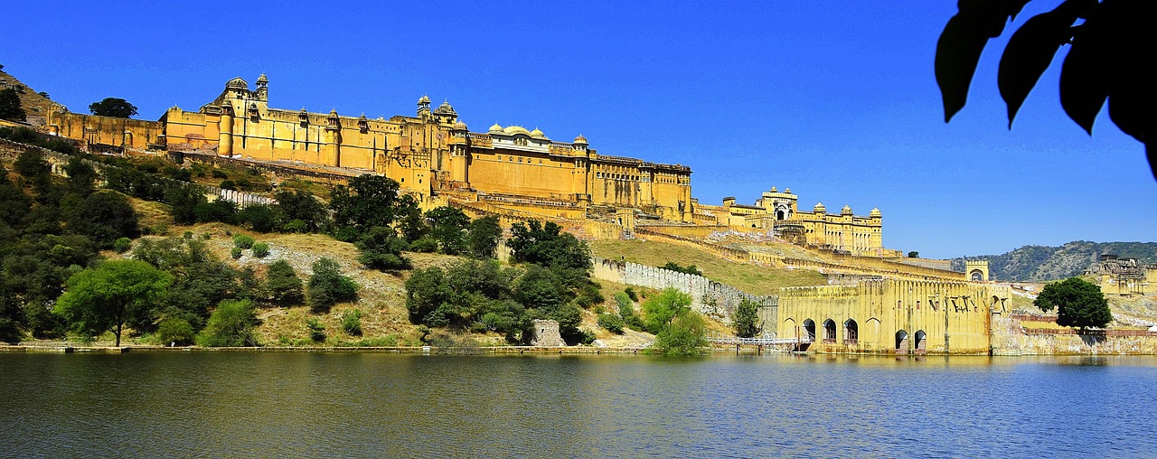 A large yellow fortress on a hill overlooking a body of water under a clear blue sky.