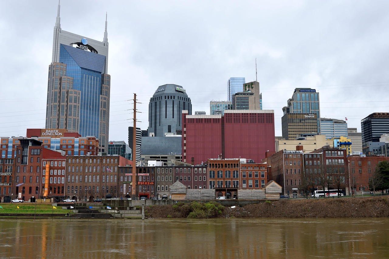 A city skyline with tall buildings along a river, featuring a mix of modern and older architecture.
