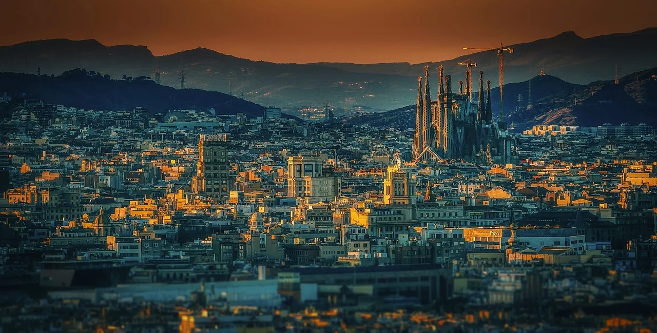 A panoramic view of Barcelona at sunset with the Sagrada Familia prominently visible.