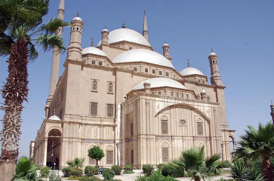 A large, ornate mosque with multiple domes and minarets under a clear blue sky.