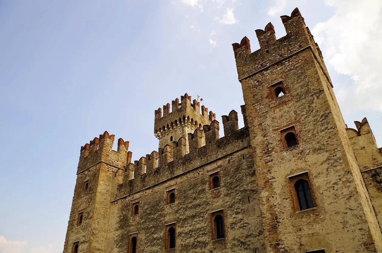 A large medieval castle with crenelated towers and stone walls under a clear sky.