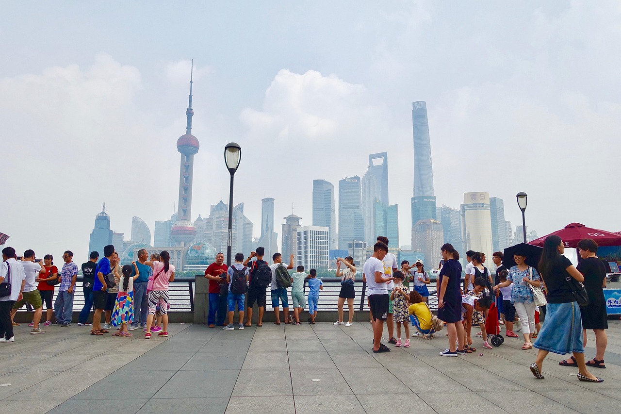 A group of tourists taking photos of the Shanghai skyline from a bridge.