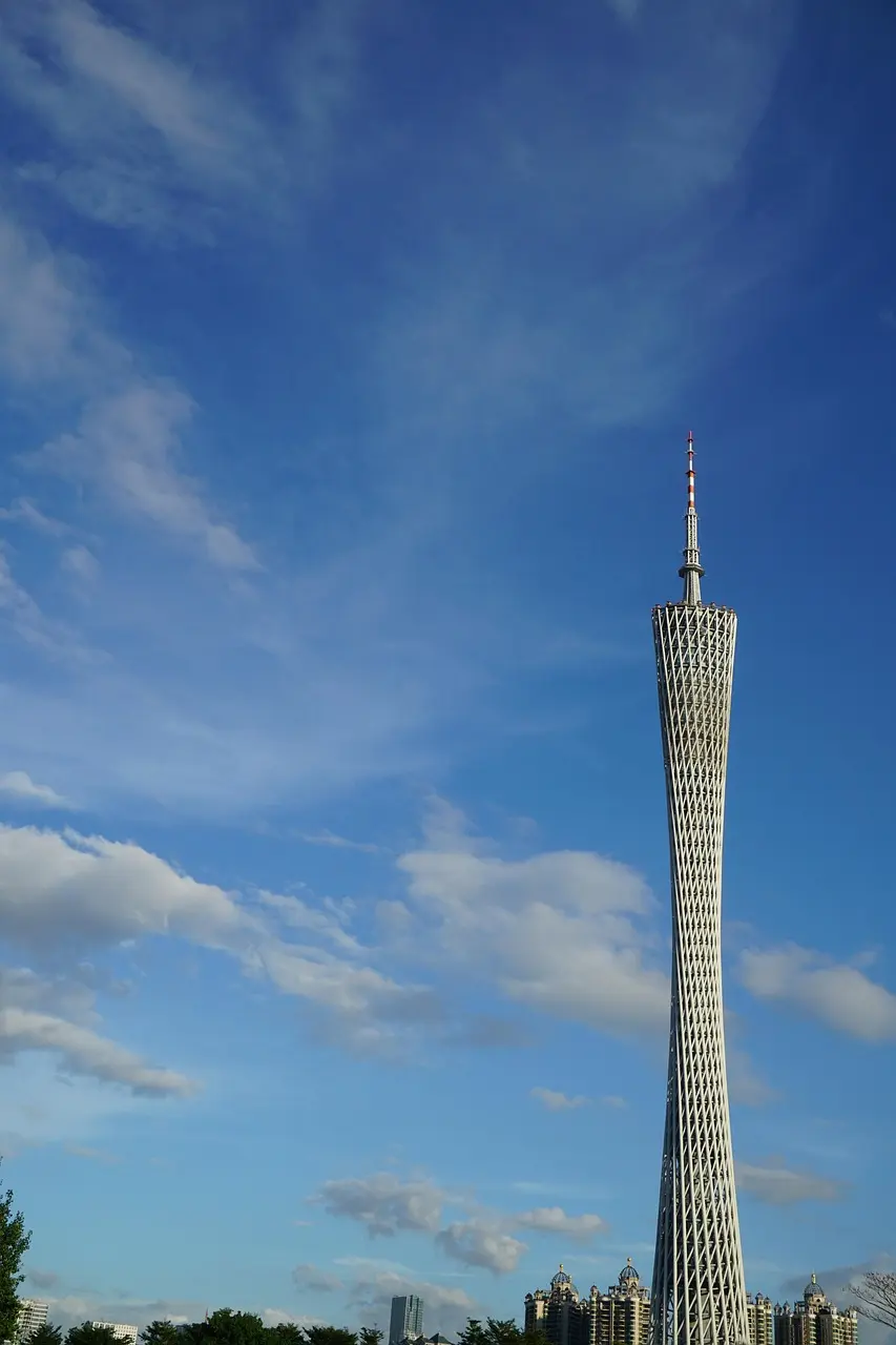 A tall, modern skyscraper with a lattice design against a blue sky with scattered clouds.