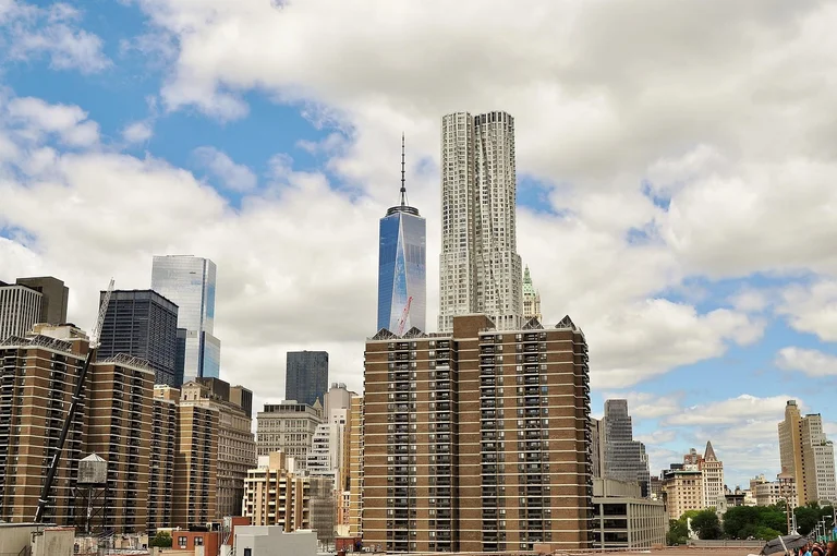 A cityscape featuring tall skyscrapers under a partly cloudy sky.
