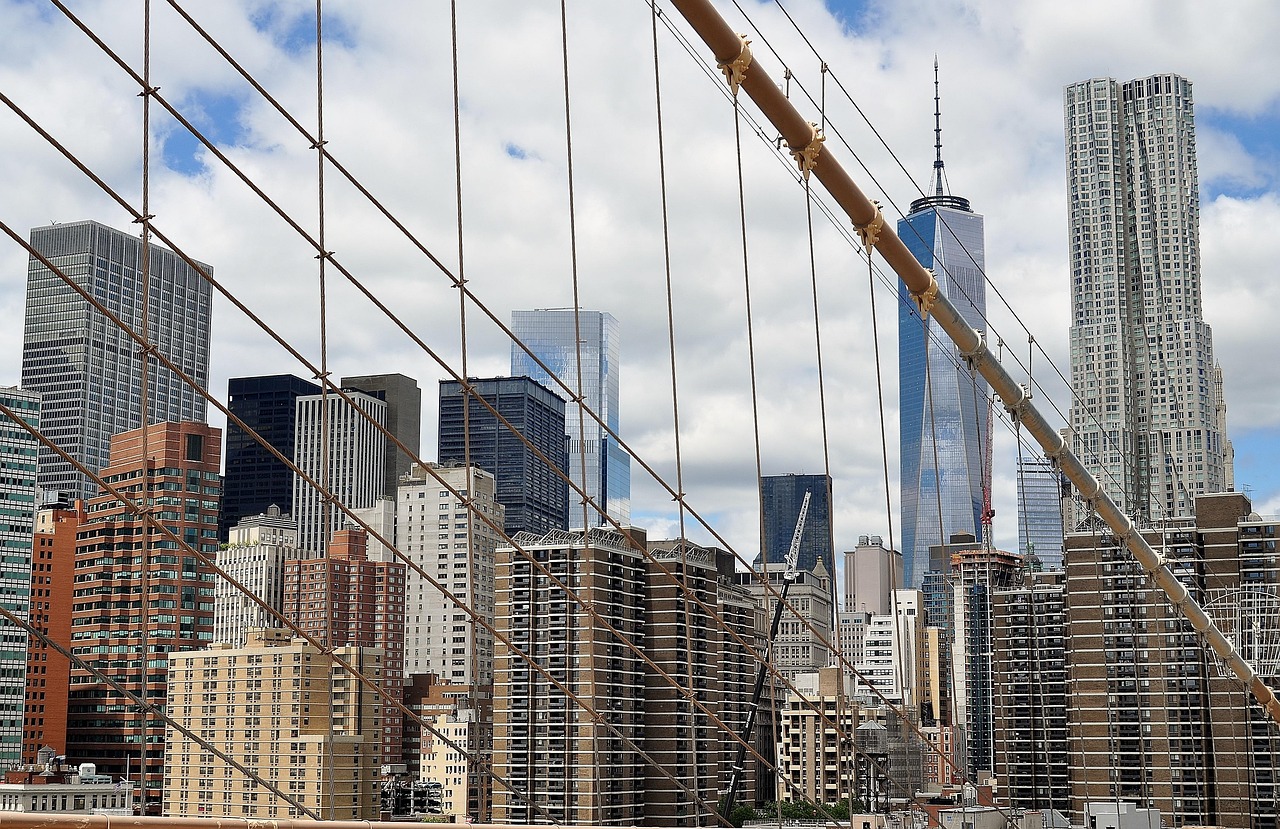 A view of the New York City skyline with tall buildings and a bridge in the foreground.