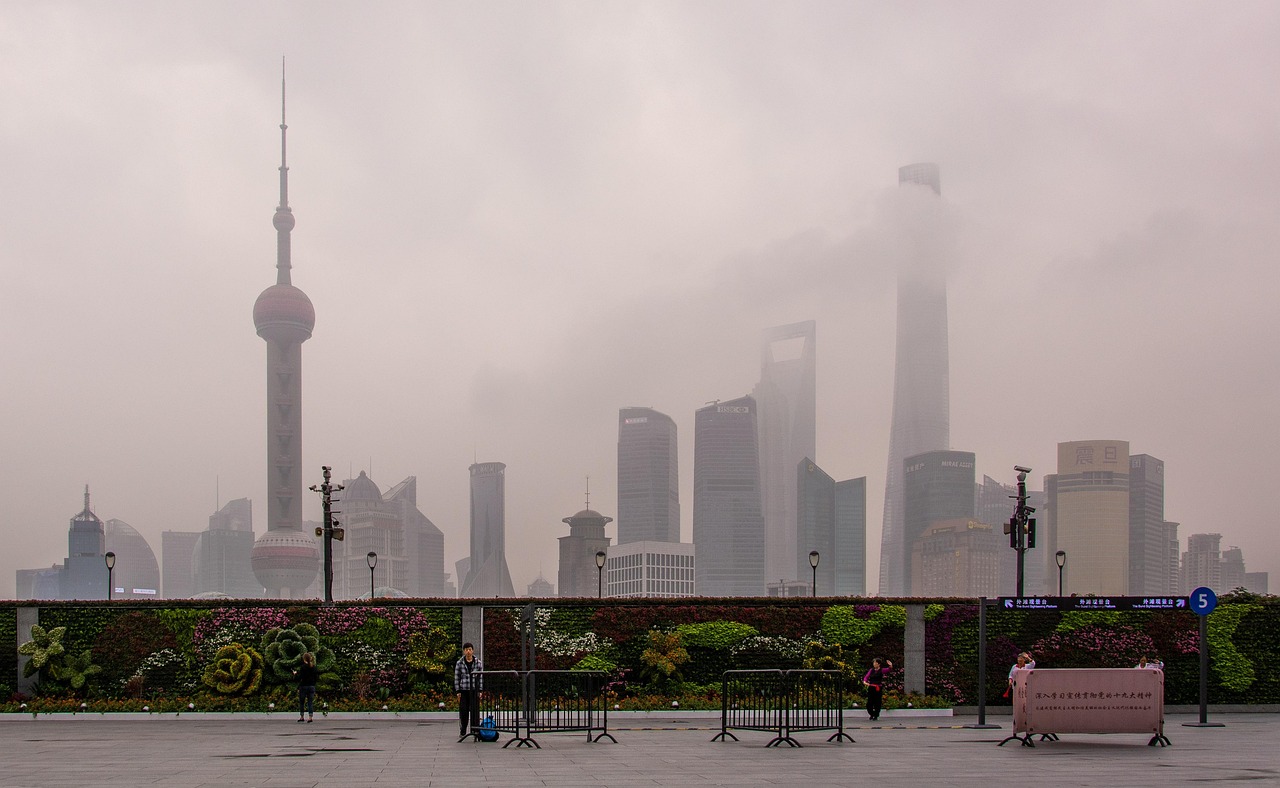 A foggy cityscape featuring tall skyscrapers and recognizable landmarks in Shanghai, China.