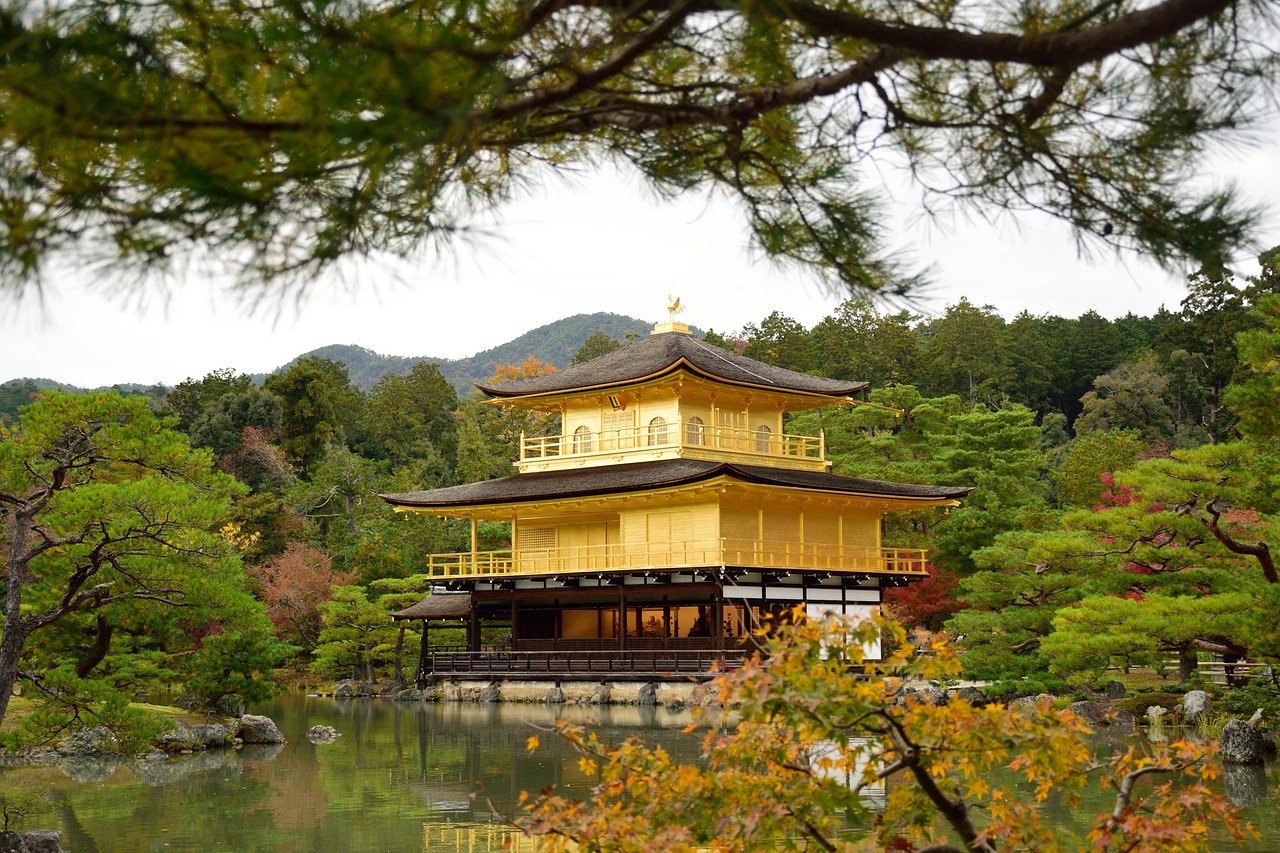 A golden pavilion surrounded by a lush garden and a pond in Kyoto, Japan.