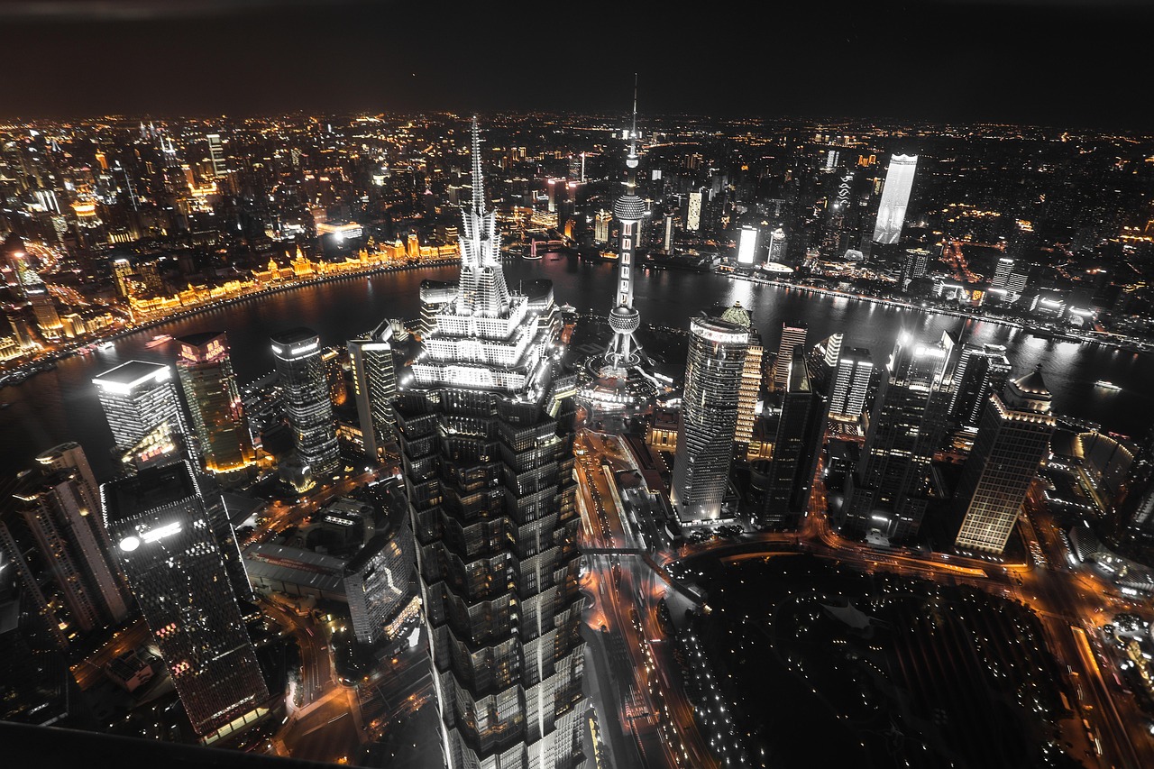 Nighttime cityscape of Shanghai with illuminated skyscrapers and the Huangpu River.