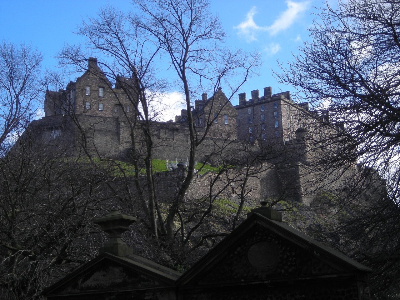 A view of Edinburgh Castle with bare trees in the foreground on a clear day.