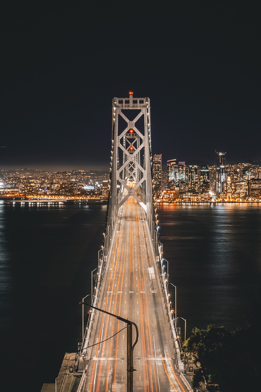 Night view of the Bay Bridge in San Francisco with city lights in the background.