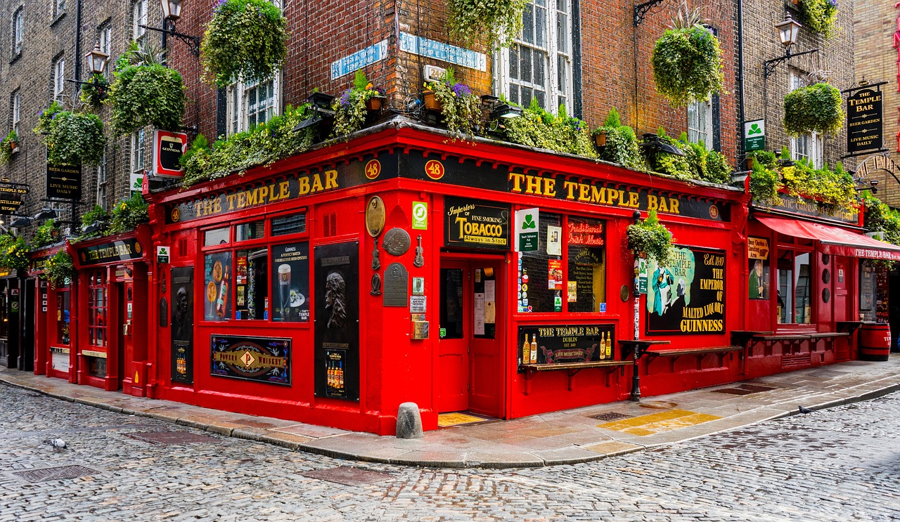 A corner view of a red pub named The Temple Bar on a cobblestone street in Dublin, Ireland.