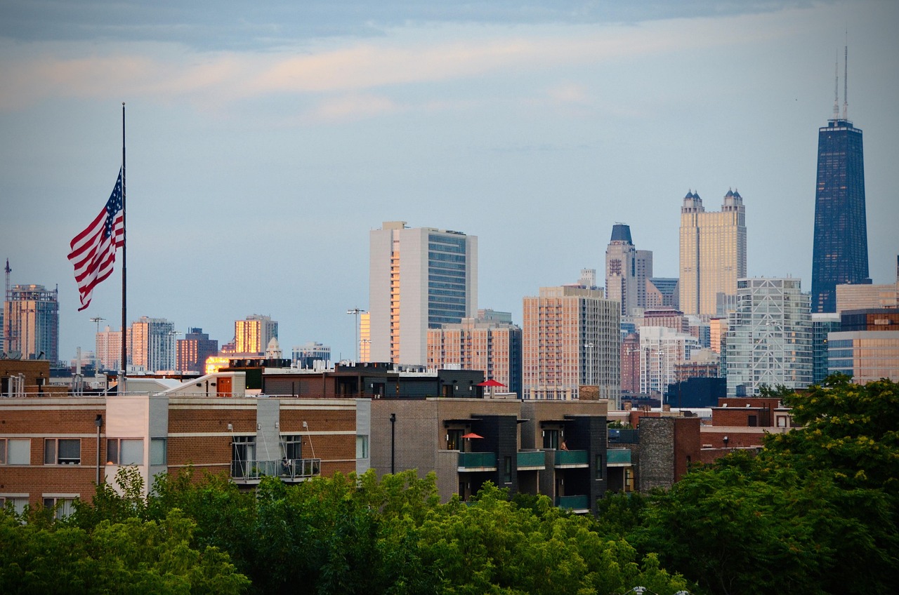 City skyline with tall buildings and an American flag in the foreground.