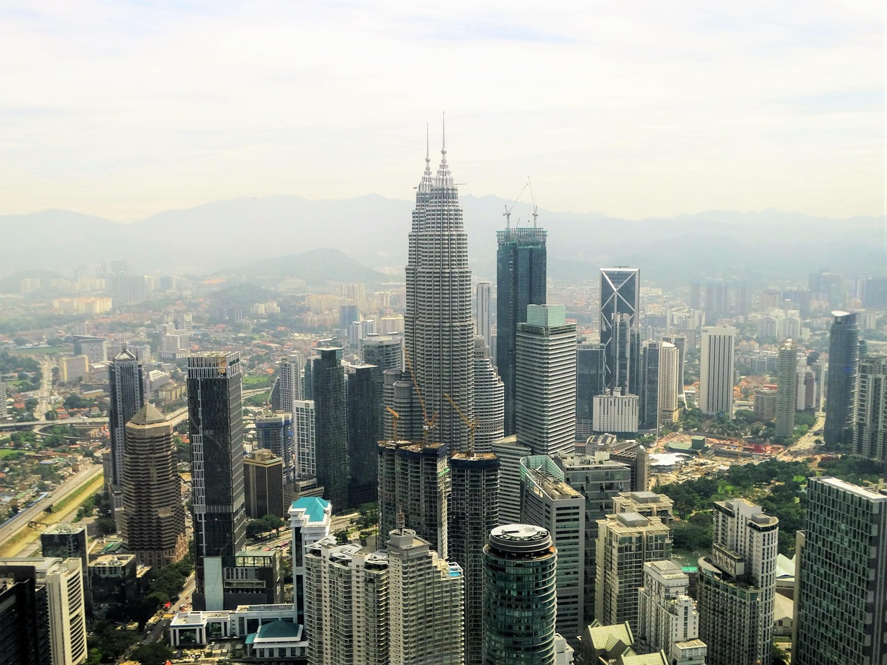 Aerial view of a city with tall skyscrapers, including the Petronas Twin Towers.