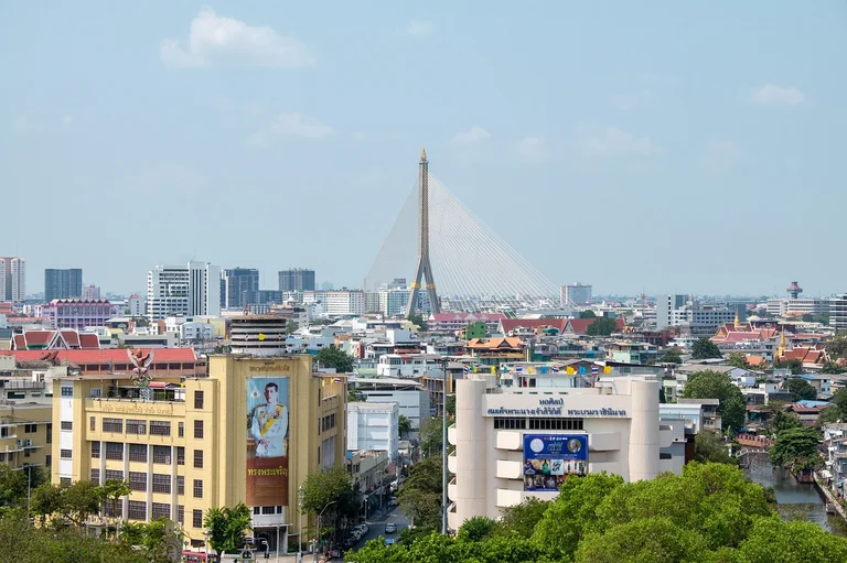 A cityscape view of Bangkok, Thailand, featuring a prominent bridge and various buildings.