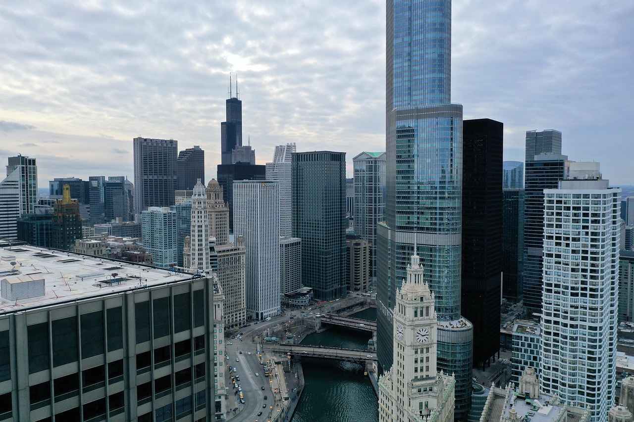 Aerial view of a city skyline with tall buildings, a river, and a bridge.
