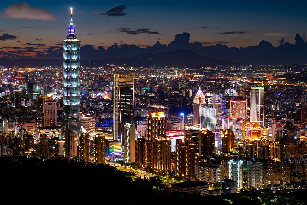 Night view of a city skyline with a tall, illuminated skyscraper prominently featured.