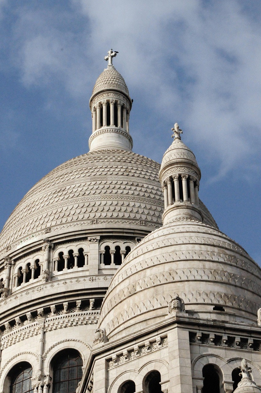 A close-up view of the domes of the Sacré-Cœur Basilica in Paris, France, against a blue sky.