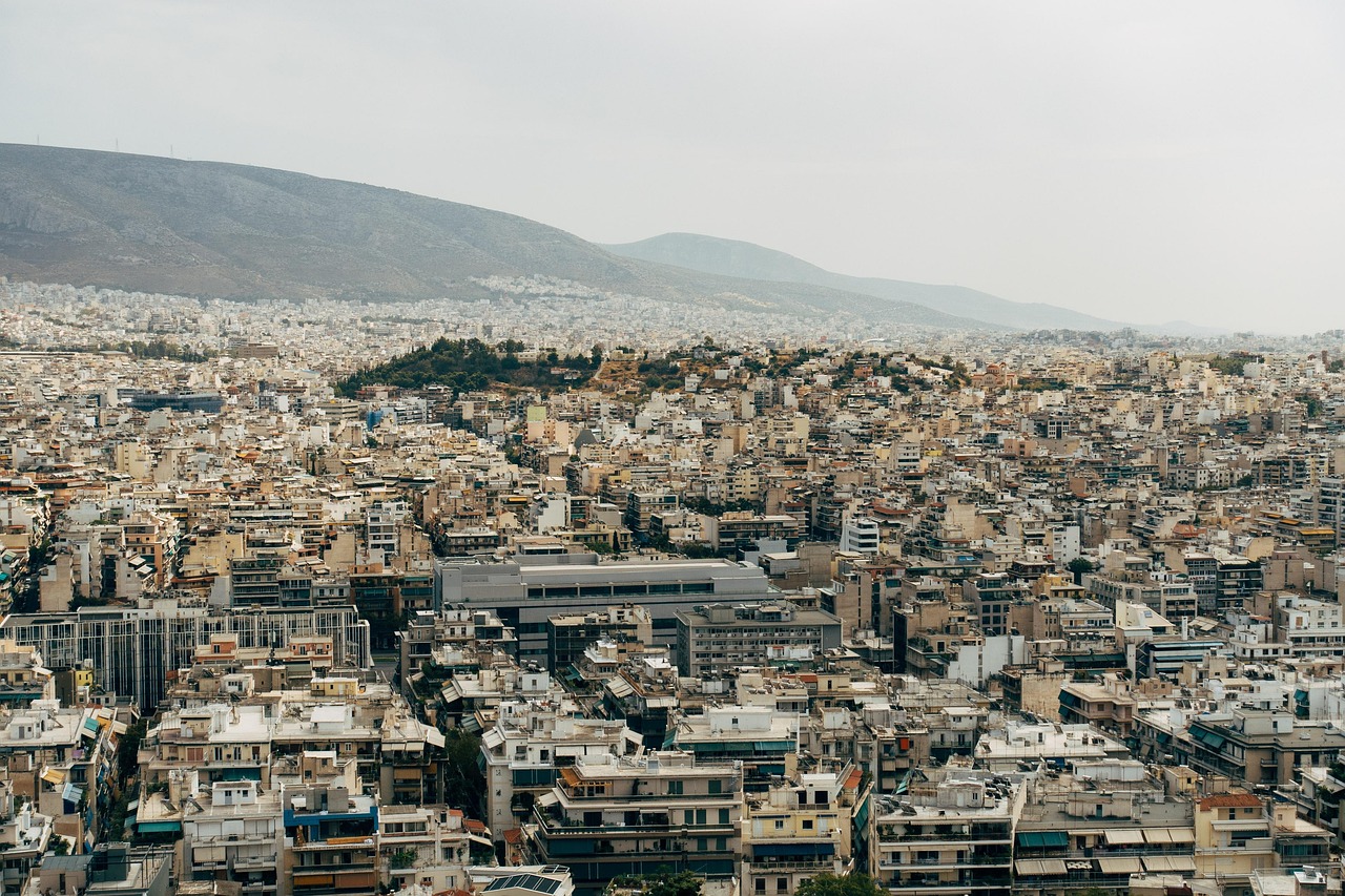Aerial view of a densely populated city with numerous buildings and a mountain in the background.