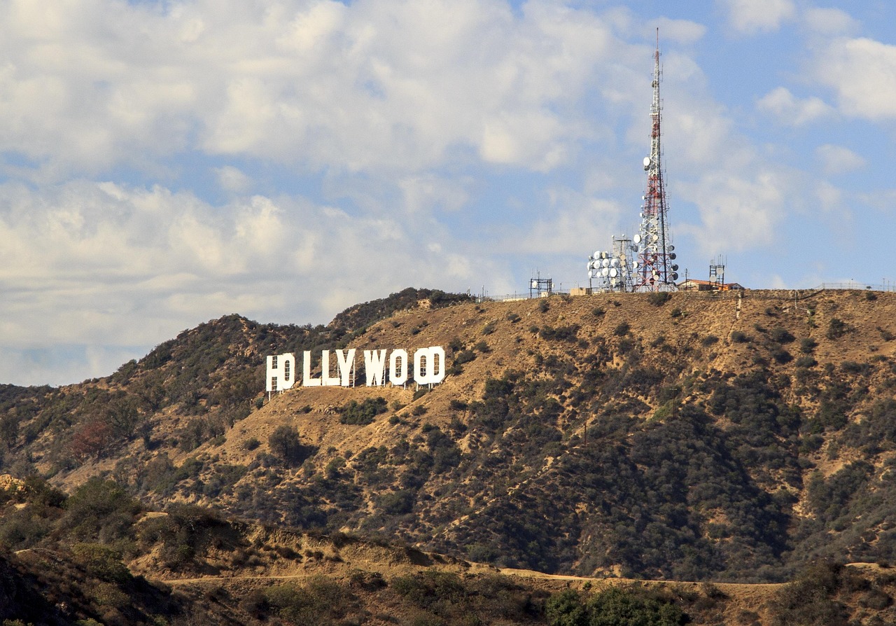A view of the Hollywood sign on a hillside with communication towers in the background.
