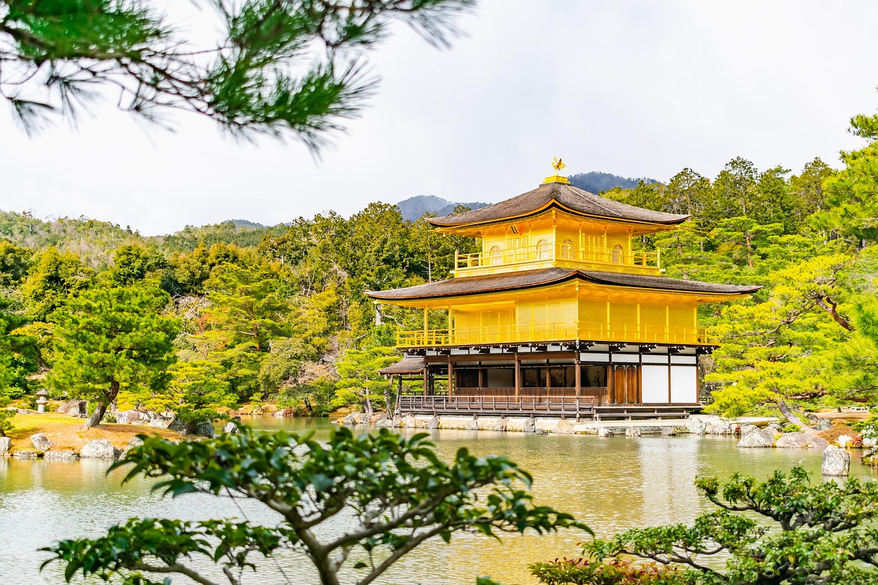 A golden pavilion surrounded by a serene pond and lush greenery.