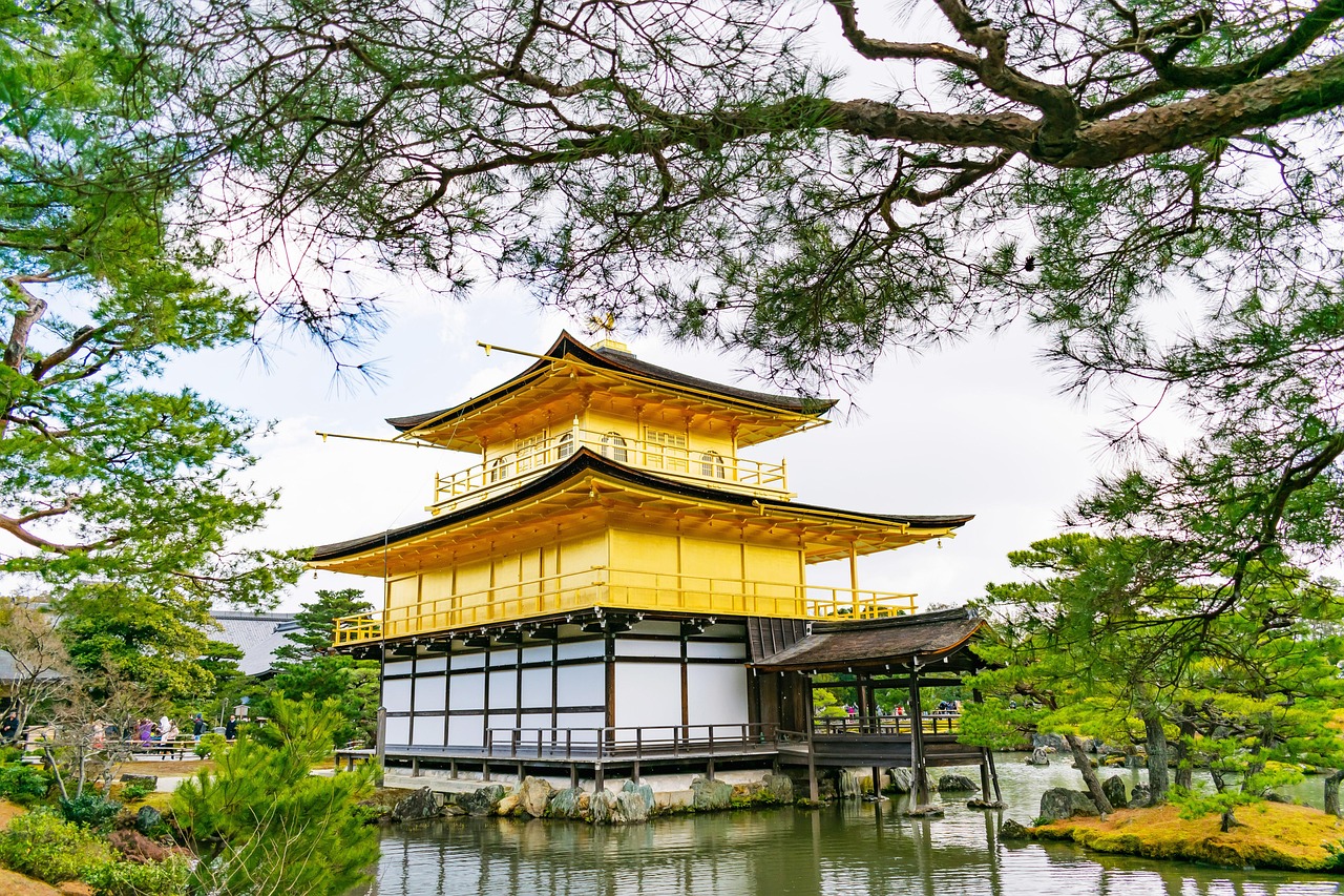 A golden pavilion surrounded by trees and a pond, reflecting traditional Japanese architecture.